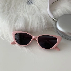 Close-up of pink cat-eye sunglasses with dark lenses on a white faux fur background