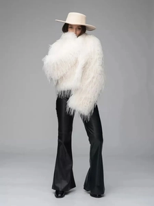 Full view of white plush faux fur coat paired with black leather flare pants