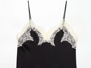 Close-up of white eyelash lace neckline on black satin camisole with silk texture