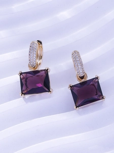 Detail of gold earrings featuring large rectangular purple gemstones and pavé zircon accents