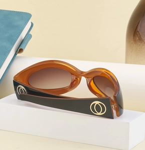 Detail of amber cat eye sunglasses with thick black temples and gold circle accents