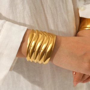 Polished gold wide wave texture stainless steel open cuff bracelet on model