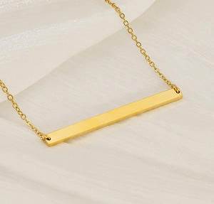 Vue macro du pendentif barre dorée polie sur fond élégant en soie blanche luxueuse