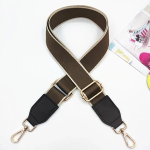 Detail of adjustable wide woven shoulder strap with brown leather ends and gold metal hooks
