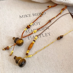 Detail showing tiger eye stone gourd pendants on wood bead and gold chains