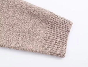 Detail of oatmeal knitted cardigan showing textured wool fabric and ribbed cuffs