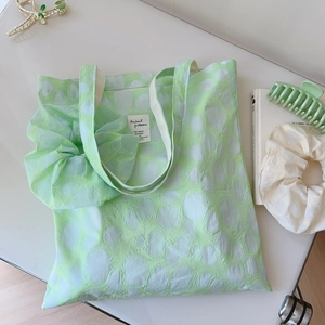 Close-up of light green floral tote bag with matching pleated scrunchies and fabric tag