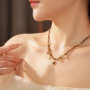 Detail of bohemian tiger eye necklace with golden sun, star and shell charms on model