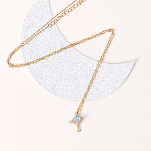 Golden Saturn planet necklace with blue orb and star pendant on moon shaped prop