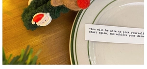 Detailed view of plush Christmas elk and Santa Claus hair tie on a warm wooden table