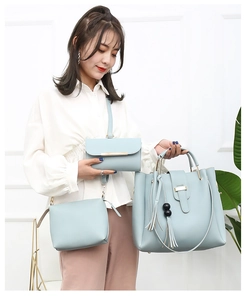 Three-piece light blue tote set with metal handle and tassel charm shown on a model
