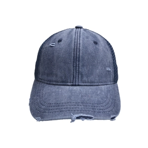 Detalle de gorra de béisbol en denim azul lavado con tejido desgastado y malla transpirable