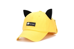Detail of yellow baseball cap featuring cute black 3D cat ears and handmade woven label