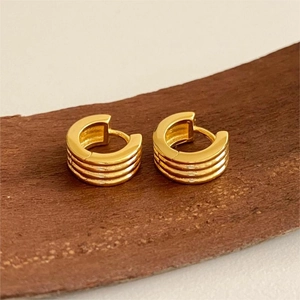 Close-up of golden triple-layered hoop earrings with a polished finish and C-shape design