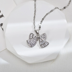 Close-up of silver bow pendant with cubic zirconia stones on a white stone base