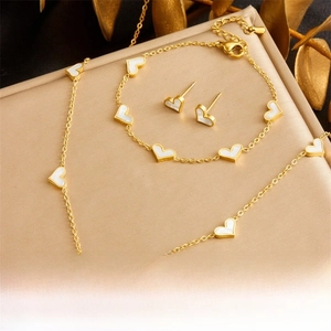 Close-up of gold-plated heart jewelry set with white shell inlay on a premium display