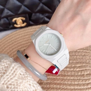 White octagonal quartz watch with silicone strap worn against a designer handbag