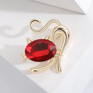 Golden cat brooch with a large red crystal oval stone on a white geometric base