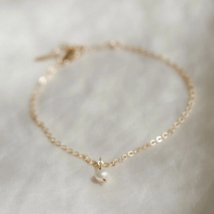 Makroaufnahme eines minimalistischen 14K vergoldeten Armbands mit einer Einzelperle