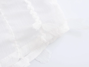 Detail of white blouse fabric texture with decorative fringe stitching and elegant finish