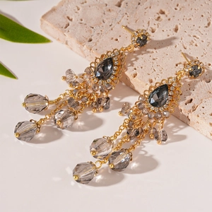 Détail de boucles d'oreilles vintage à pompons dorés avec pierres grises en forme de goutte