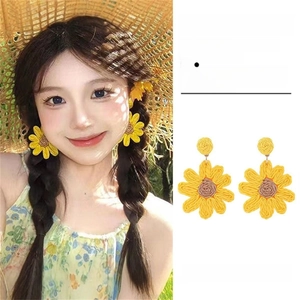 Detail of yellow woven sunflower earrings with brown core on model and white background