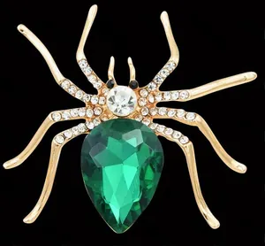 Detailed macro view of a spider brooch featuring a green pear-cut crystal and rhinestones