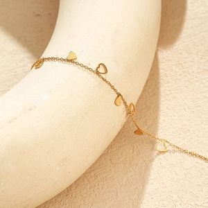 Gros plan d'un bracelet en acier inoxydable doré avec des breloques en forme de cœur évidé