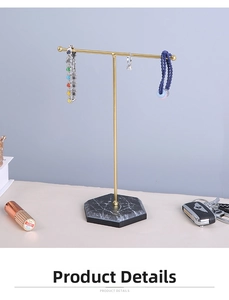 Macro view of T-bar gold jewelry stand with white marble base for necklace and ring storage