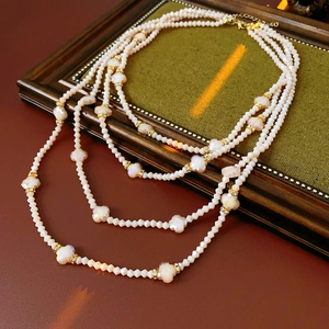 Vue détaillée du collier de perles multicouche avec fleurs et entretoises dorées serties