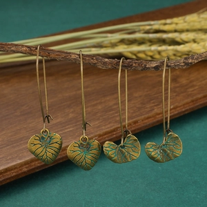 Vue détaillée des boucles d'oreilles feuilles en bronze vintage sur branches en bois