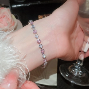 Close-up of pink and white star-shaped zircon bracelet on wrist with elegant accessories
