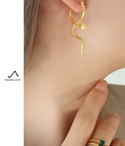 Close-up of golden snake wrap earrings and twisted ring in polished stainless steel