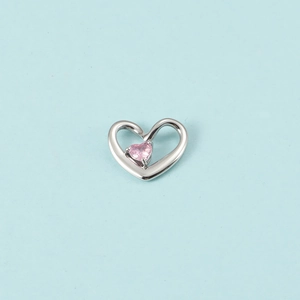Vue macro d'un pendentif cœur argenté avec pierre de naissance rose sur fond bleu clair