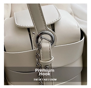 Detail of silver metal hook and fine chain connection on stylish off-white PU box bag