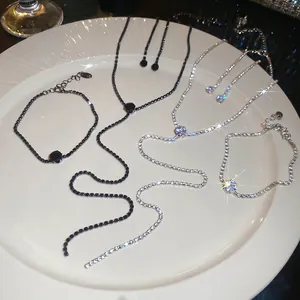 Sparkling silver and black rhinestone necklace and bracelet sets on a white plate