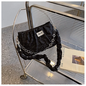Detail of black pleated bag with silver floral chain on a modern metal display stand