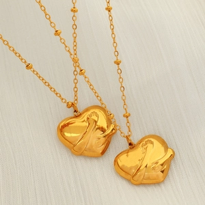 Golden heart pendant necklace with hugging hands relief and beaded chain detail