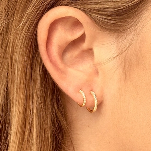 Luxurious gold double hoop earrings with pave-set cubic zirconia shown on model
