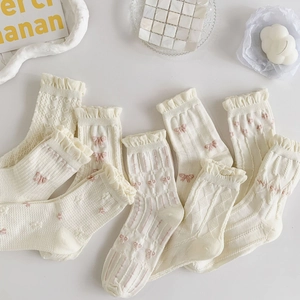 Detailed view of white ruffle socks with pink bow patterns and textured knit fabric