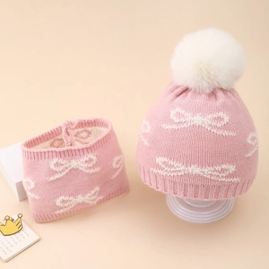 Detailed view of pink knitted baby hat and scarf set with white bow jacquard patterns