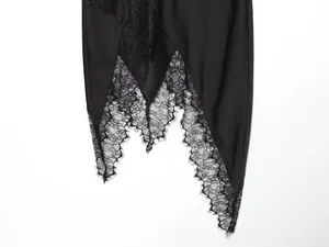 Detail of irregular hemline with delicate black lace embroidery on smooth black skirt