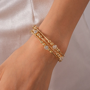 Detailed view of triple-layer gold beaded bracelet featuring shimmering zircon accents
