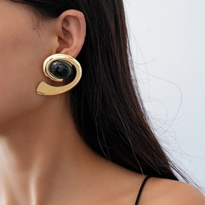 Macro detail of retro geometric oval earring with golden spiral texture and black gemstone