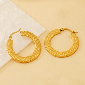 Golden stainless steel hoop earrings with star texture on beige silk background