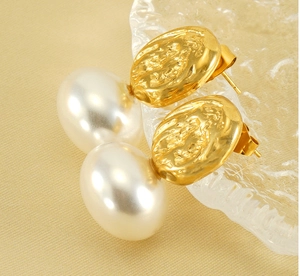 Close-up of vintage golden textured metal earrings with elegant white pearl pendants