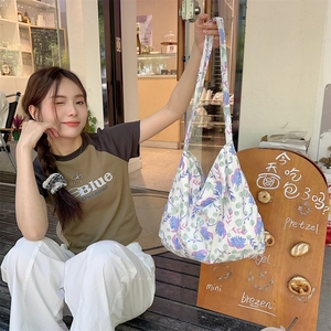 Floral canvas tote bag with purple and blue flower patterns shown in a lifestyle cafe scene