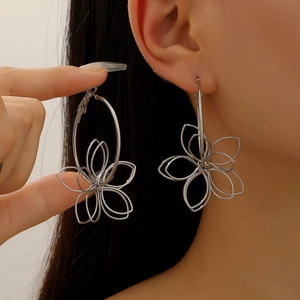 Close-up of oversized hollow flower earrings in silver finish showing size and fit