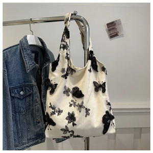 Detailed close-up of intricate black butterfly embroidery on a white canvas tote bag