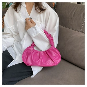 Detailed view of magenta pleated cloud bag with soft PU leather handle on a sofa